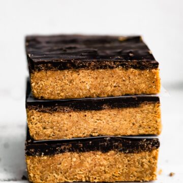 Three no bake chocolate almond flour bars stacked on a white countertop.