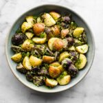 Halved baby potatoes coated in a creamy herb sauce in a bowl.