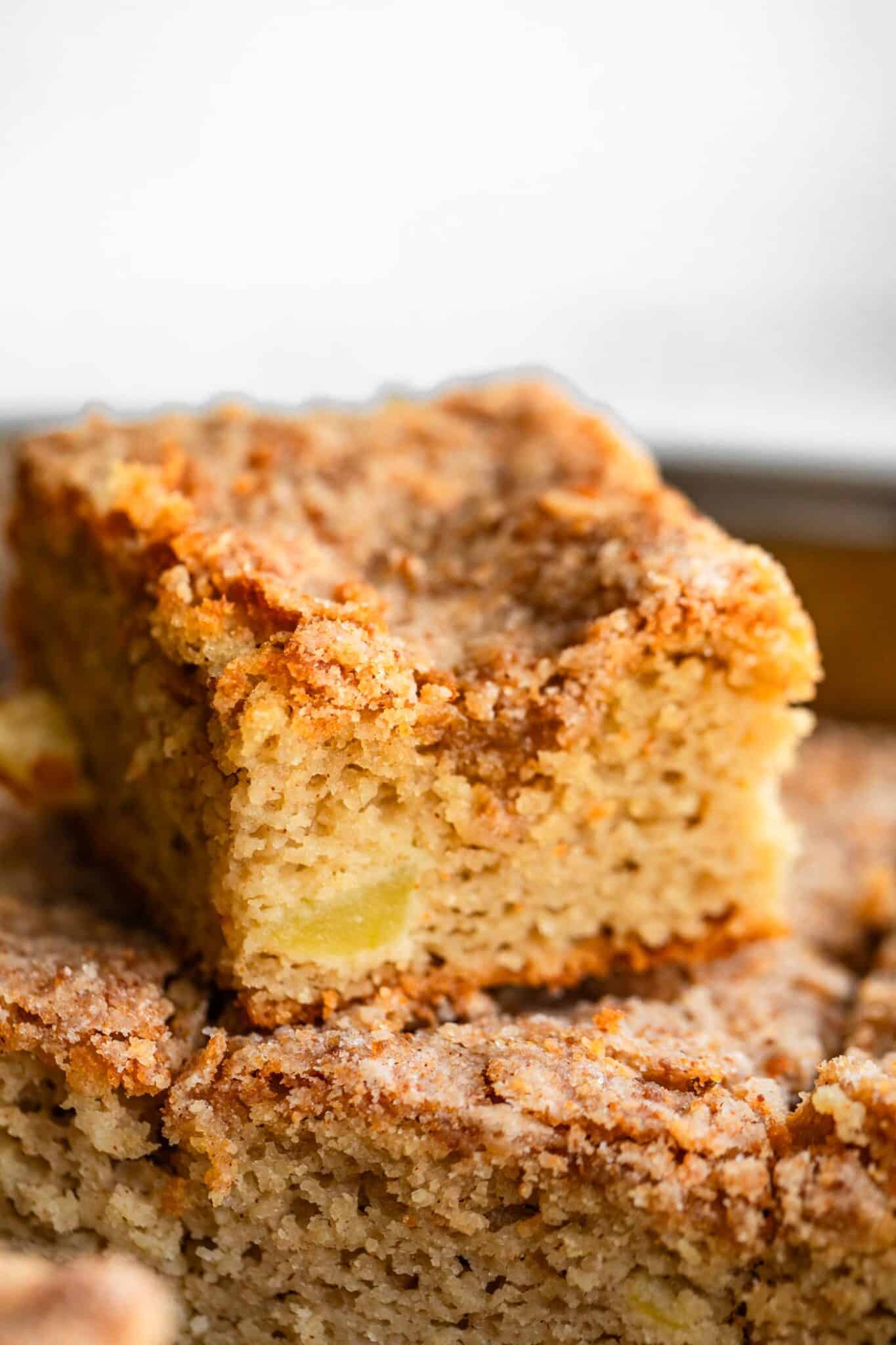 Close-up of sliced apple coffee cake showing moist crumb with bits of apple inside.