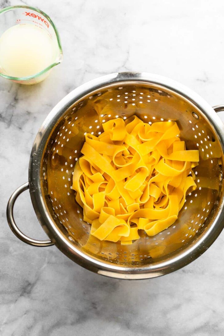 gluten-free pasta in a strainer with reserved water in a glass measuring jar