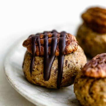 Close-up shot of pecan pie balls on a plate, highlighting the chocolate drizzle and pecan topping