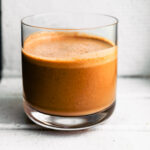 Single glass of chocolate coconut smoothie set against a bright white background.