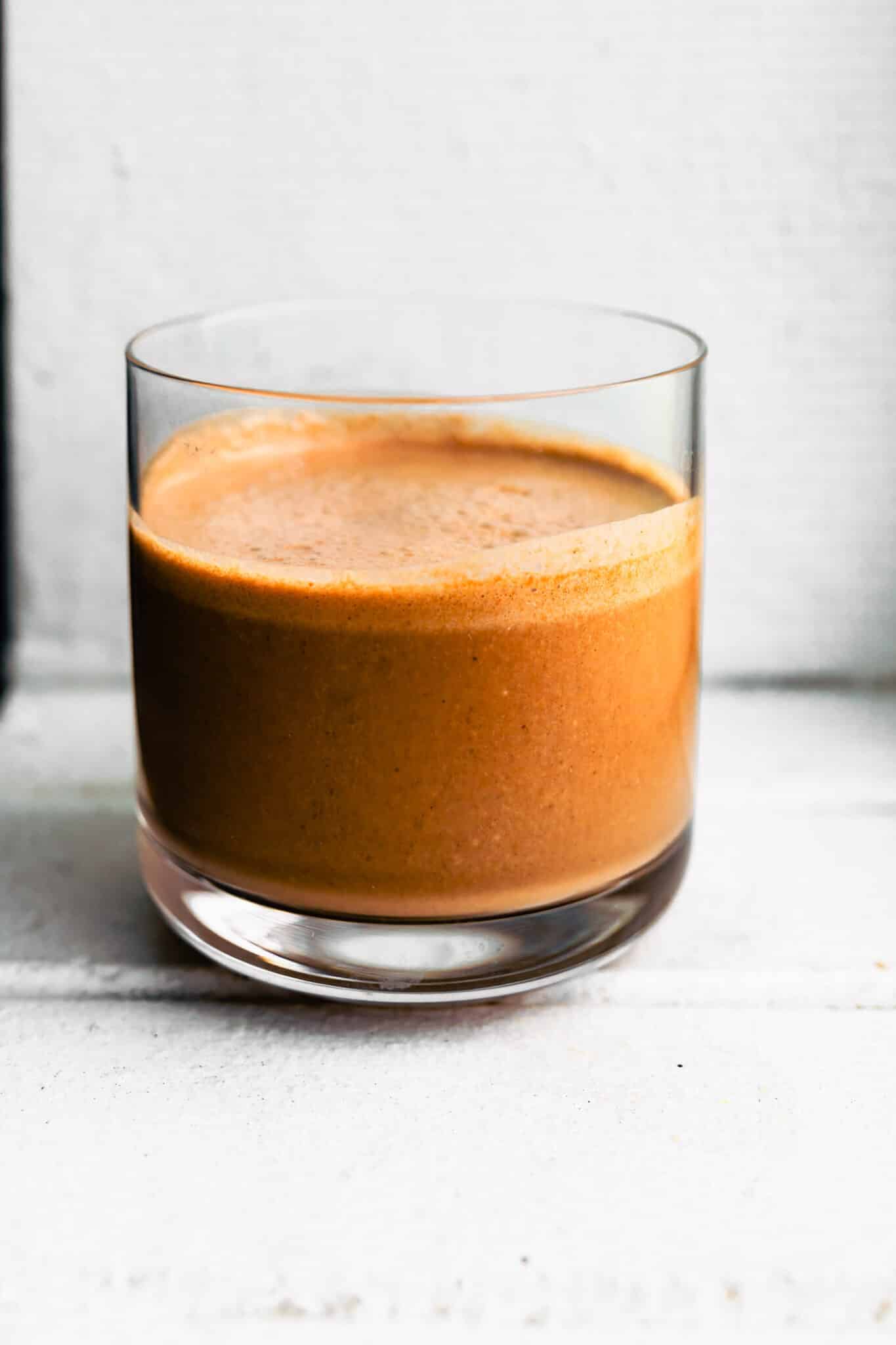 Single glass of chocolate coconut smoothie set against a bright white background.