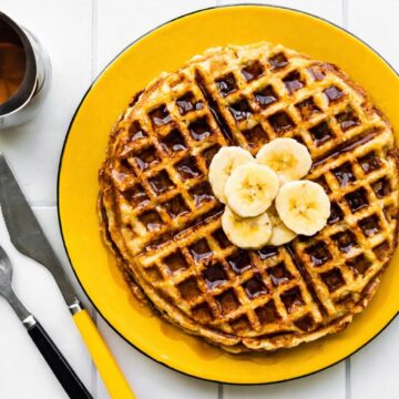 Gluten-Free Banana waffles with syrup and bananas, yellow plate, utensils