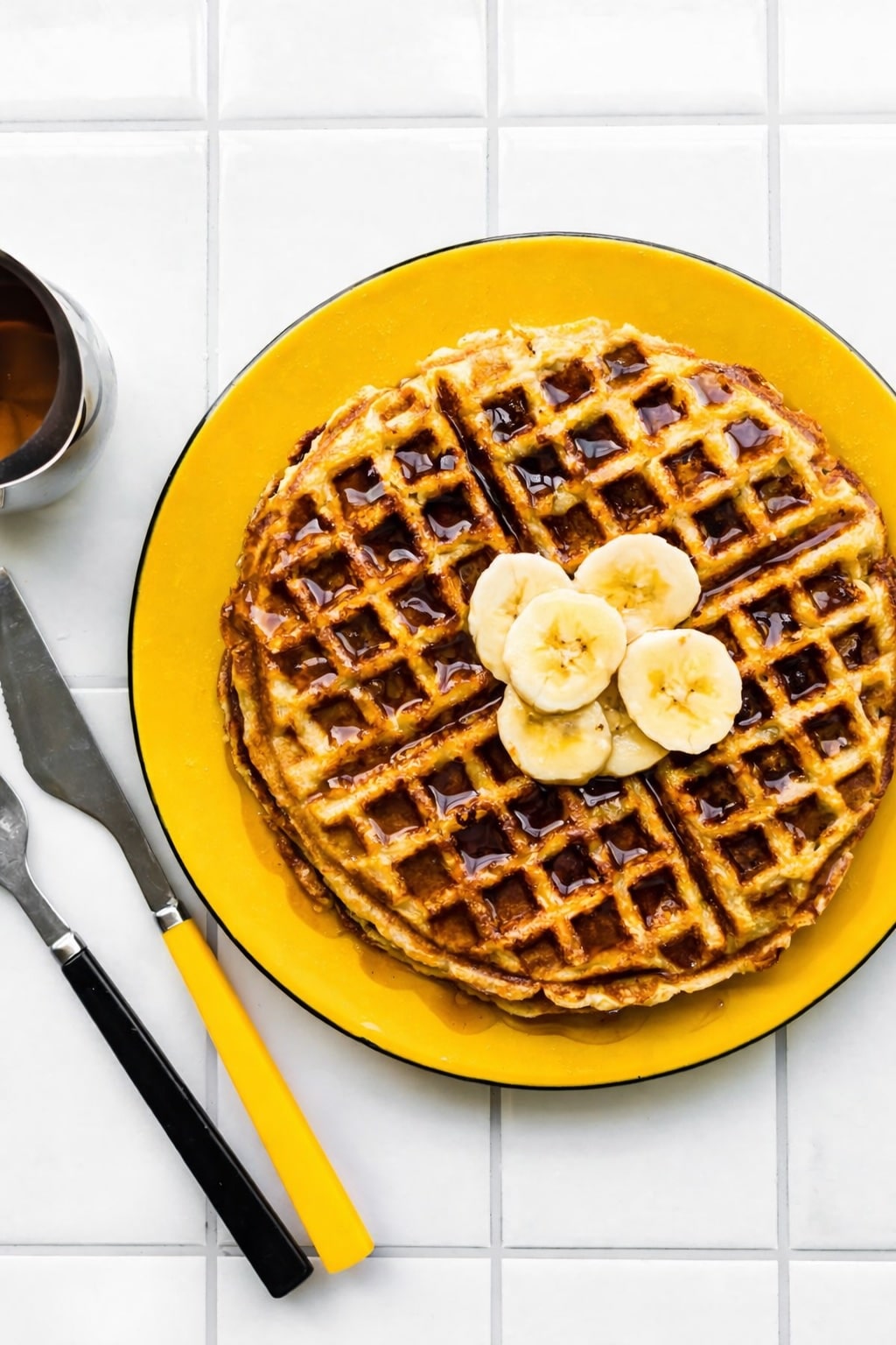 Gluten-Free Banana waffles with syrup and bananas, yellow plate, utensils