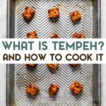 Marinated cubed of tempeh on a baking sheet with a text overlay for pinterest.