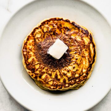2. Stack of gluten-free pancakes on a white plate with a pat of butter melting on top.