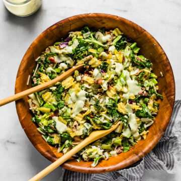 Chopped pickle salad tossed with creamy dressing and topped with crushed chips in a wooden bowl.