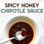 A spoon being dipped into a bowl of honey chipotle sauce with a text overlay for pinterest.