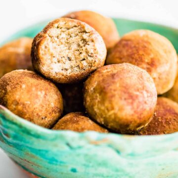 cinnamon bites in turquoise bowl, top protein ball has bite taken out to show inside texture.