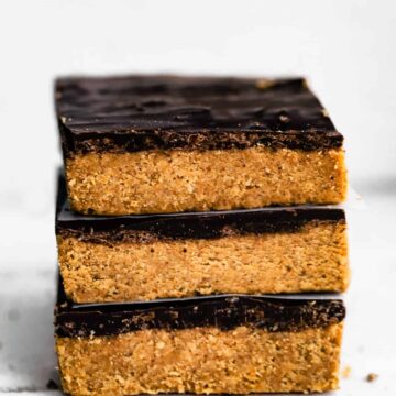Three no bake chocolate almond flour bars stacked on a white countertop.