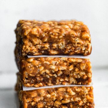 A stack of three homemade protein bars with wax paper between them.